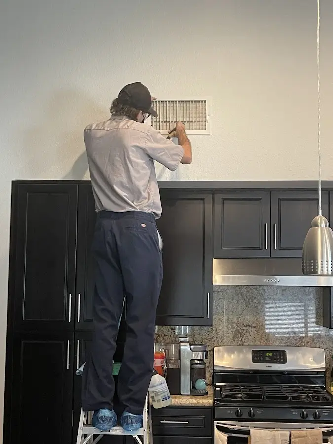 Technician inspecting an air vent during HVAC service in Sterling